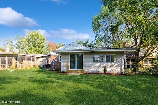 rear view of property featuring a sunroom and a yard