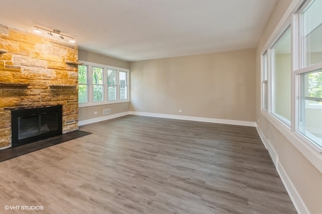 unfurnished living room with a fireplace, dark hardwood / wood-style flooring, and track lighting