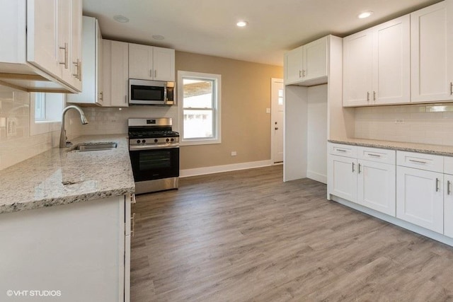 kitchen with light wood finished floors, a sink, white cabinetry, and appliances with stainless steel finishes