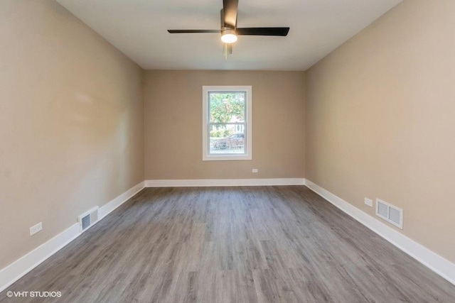 unfurnished room with baseboards, ceiling fan, visible vents, and wood finished floors