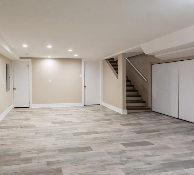 basement with light wood-type flooring and electric panel