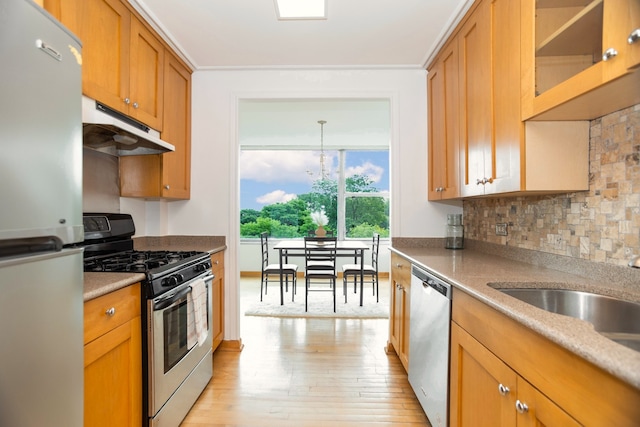 kitchen featuring pendant lighting, sink, tasteful backsplash, appliances with stainless steel finishes, and light hardwood / wood-style floors