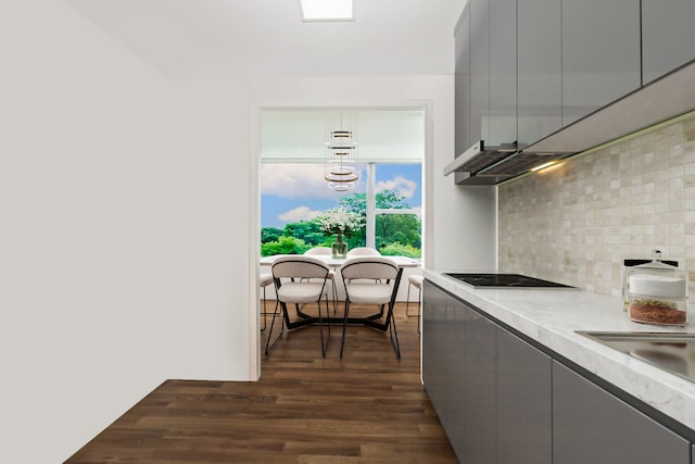 kitchen featuring sink, backsplash, black electric cooktop, gray cabinets, and dark hardwood / wood-style flooring