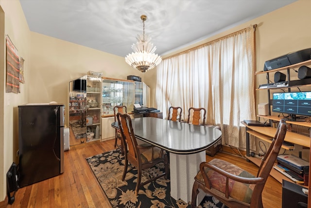 dining area featuring wood-type flooring, an inviting chandelier, and plenty of natural light