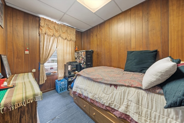 bedroom featuring wooden walls, carpet floors, and a paneled ceiling