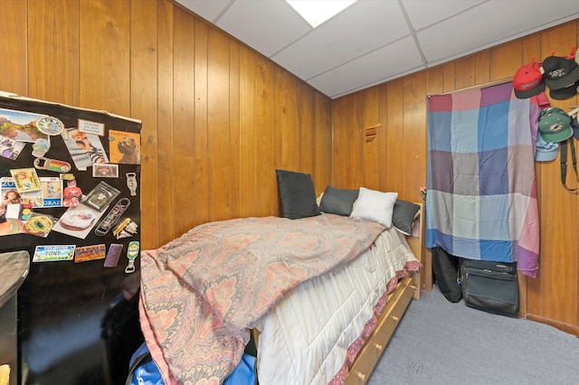 carpeted bedroom with wooden walls and a drop ceiling