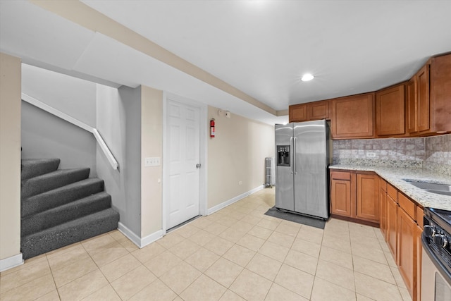 kitchen featuring light stone counters, sink, light tile patterned floors, backsplash, and stainless steel appliances