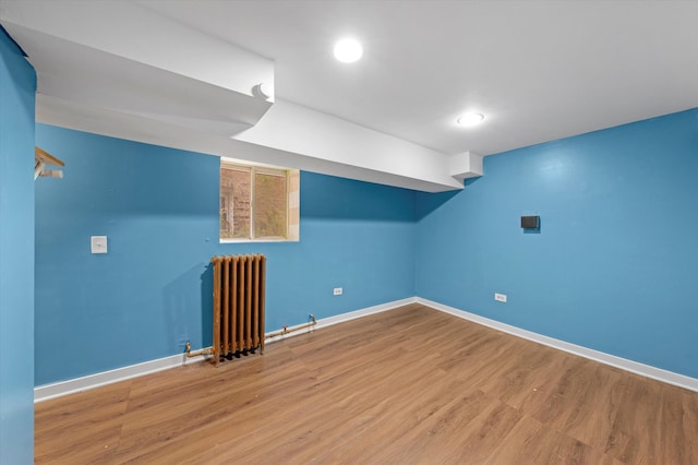 basement featuring radiator and hardwood / wood-style floors