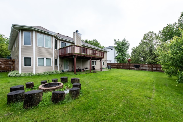 rear view of property with a yard, a deck, and a fire pit