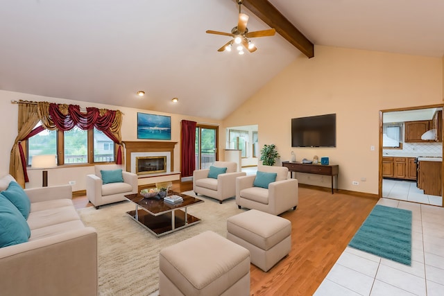 living room with light hardwood / wood-style flooring, ceiling fan, beamed ceiling, and a wealth of natural light