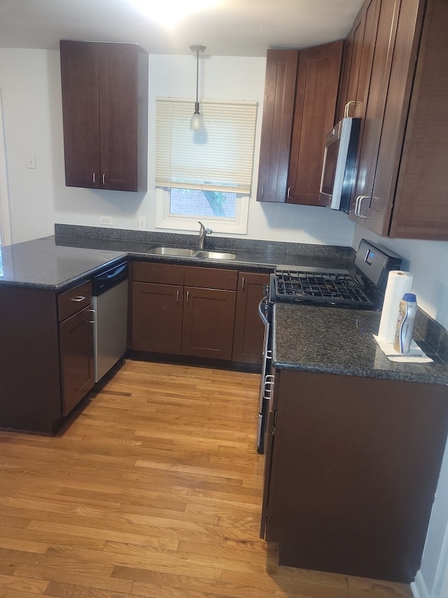 kitchen featuring light wood-type flooring, appliances with stainless steel finishes, sink, and pendant lighting