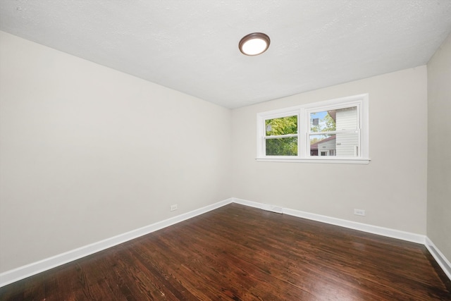 empty room featuring a textured ceiling and dark hardwood / wood-style flooring