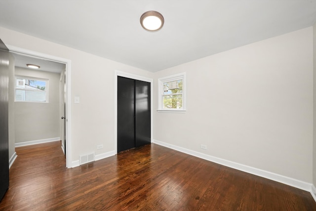 unfurnished bedroom featuring a closet and dark hardwood / wood-style flooring