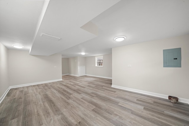 basement featuring electric panel and light hardwood / wood-style flooring