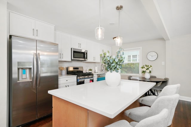 kitchen with pendant lighting, dark wood-type flooring, white cabinetry, decorative backsplash, and stainless steel appliances