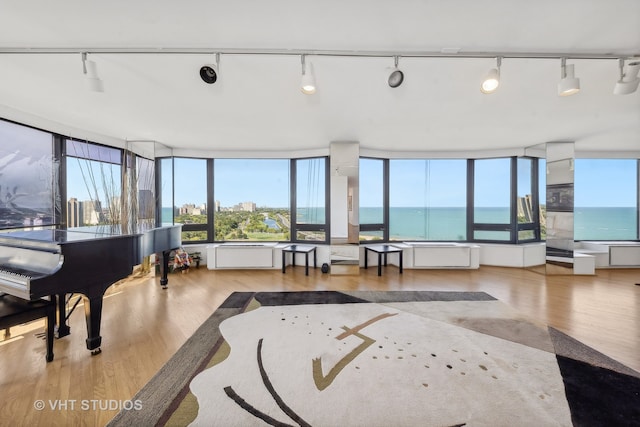 living room featuring rail lighting, a water view, and hardwood / wood-style flooring