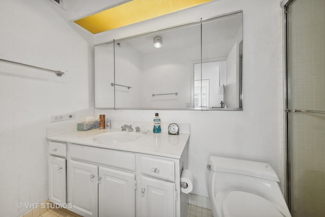 bathroom with tile patterned flooring, a shower with shower door, vanity, and toilet