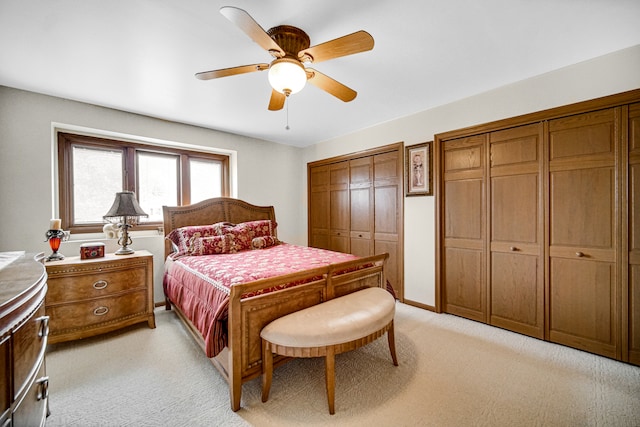 bedroom with light carpet, multiple closets, and ceiling fan