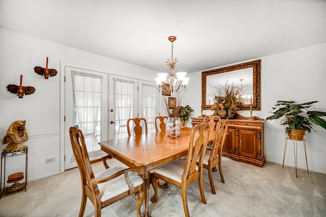 dining space with french doors, an inviting chandelier, and light colored carpet