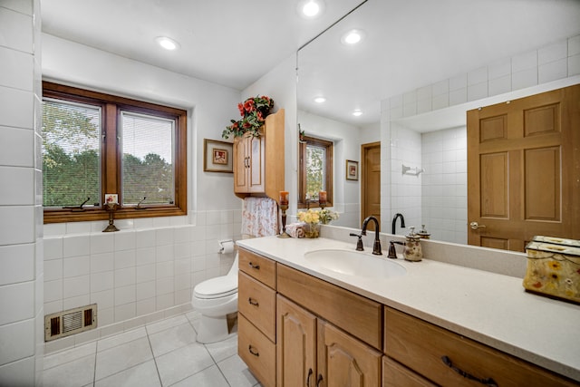 bathroom with vanity, toilet, tile walls, and a wealth of natural light