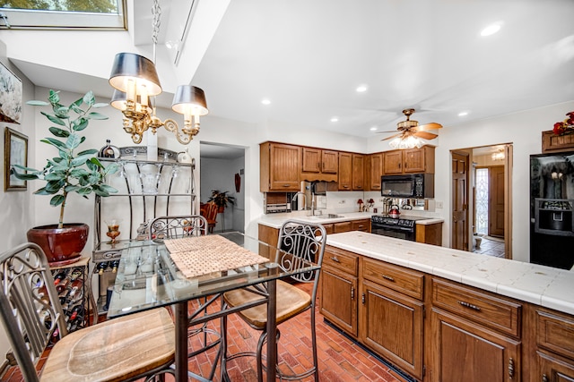 kitchen with light stone countertops, ceiling fan, black appliances, and sink