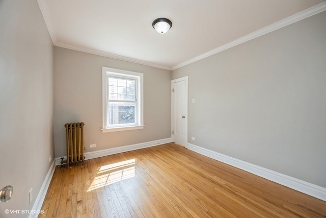 spare room featuring ornamental molding, radiator, and light hardwood / wood-style flooring