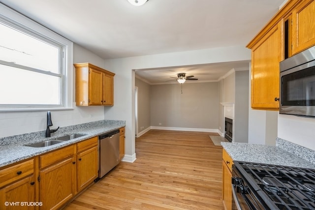 kitchen with ornamental molding, appliances with stainless steel finishes, sink, and light hardwood / wood-style flooring