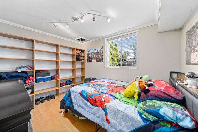 bedroom featuring hardwood / wood-style flooring, ornamental molding, and rail lighting