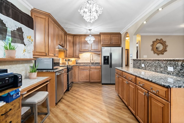 kitchen featuring pendant lighting, stainless steel appliances, a chandelier, and light hardwood / wood-style flooring