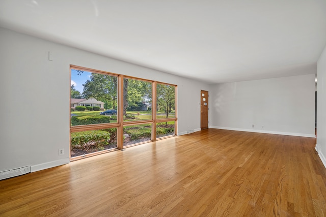 unfurnished room with a baseboard radiator and light wood-type flooring