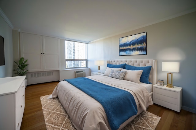 bedroom with ornamental molding, hardwood / wood-style floors, radiator heating unit, and an AC wall unit