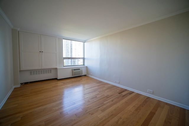 unfurnished bedroom featuring light hardwood / wood-style flooring, ornamental molding, and a wall unit AC