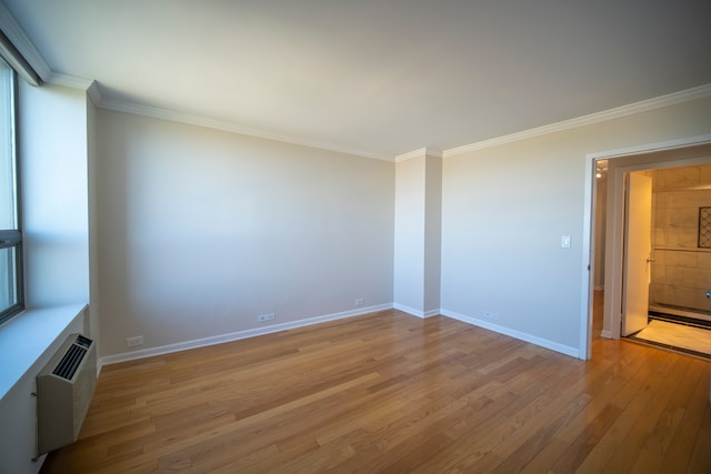 spare room featuring light wood-type flooring, crown molding, and a wall mounted air conditioner