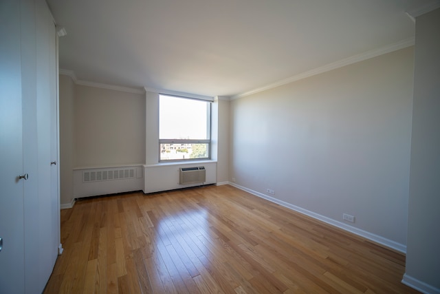 spare room featuring crown molding, light hardwood / wood-style floors, a wall mounted AC, and radiator heating unit