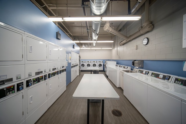 laundry room with stacked washer and clothes dryer, dark hardwood / wood-style flooring, and washing machine and clothes dryer