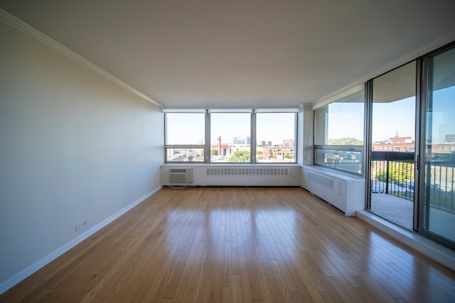 empty room with light hardwood / wood-style floors, ornamental molding, a wall mounted AC, and radiator