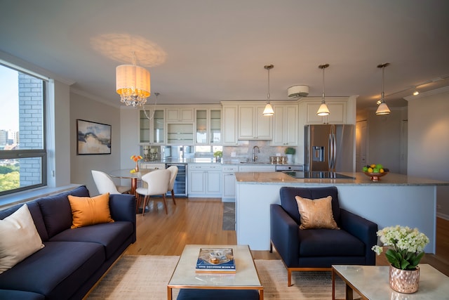 living room featuring an inviting chandelier, light hardwood / wood-style flooring, crown molding, and sink