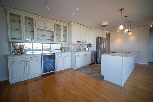 kitchen featuring pendant lighting, wine cooler, sink, light hardwood / wood-style flooring, and appliances with stainless steel finishes