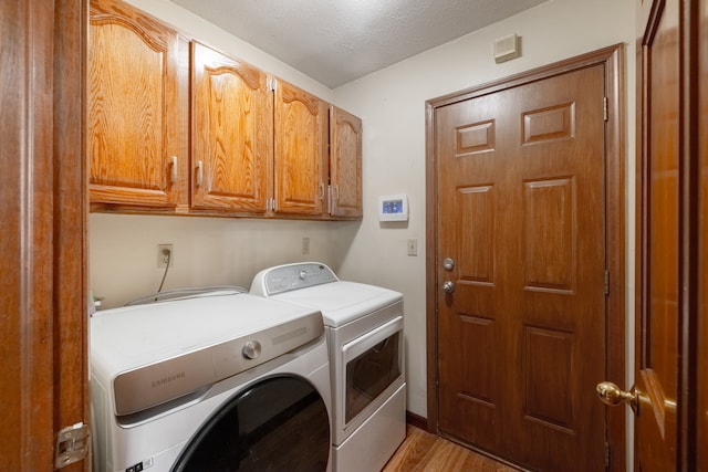 clothes washing area featuring light hardwood / wood-style floors, a textured ceiling, separate washer and dryer, and cabinets