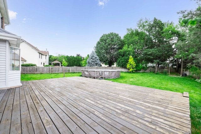 wooden deck with a fenced in pool and a yard