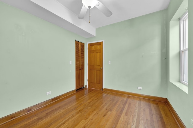 spare room featuring ceiling fan, light wood-type flooring, and a healthy amount of sunlight