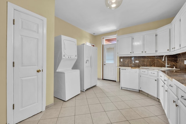 kitchen with white cabinets, stacked washer / drying machine, sink, and white appliances