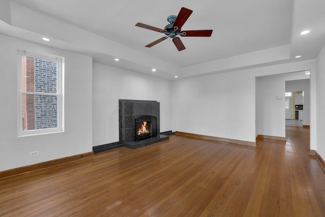 unfurnished living room with ceiling fan, hardwood / wood-style floors, and a tile fireplace