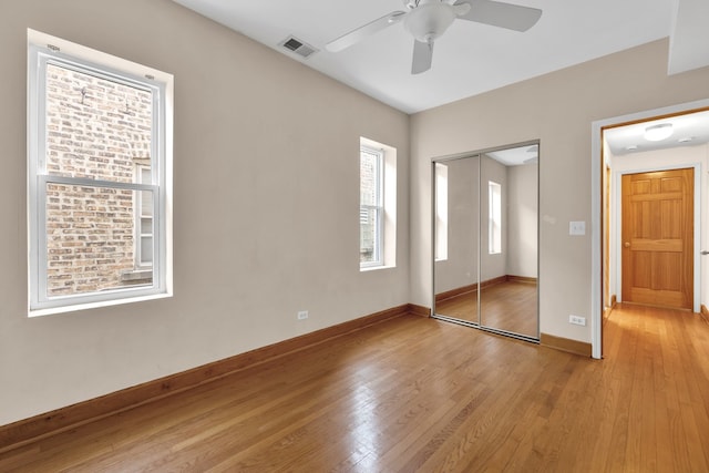 unfurnished bedroom with ceiling fan, light wood-type flooring, a closet, and multiple windows