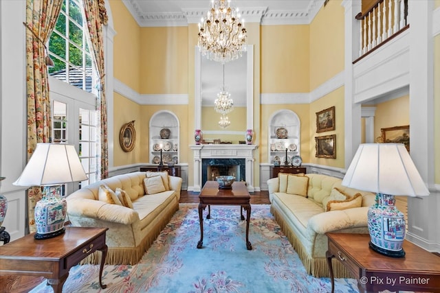 living room with built in shelves, ornamental molding, a high end fireplace, hardwood / wood-style flooring, and an inviting chandelier