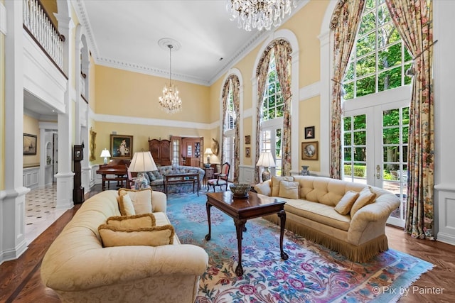 interior space featuring french doors, an inviting chandelier, a towering ceiling, and ornamental molding