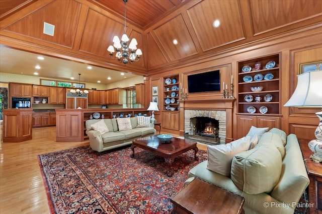 living room featuring built in features, a stone fireplace, wooden ceiling, a notable chandelier, and light hardwood / wood-style floors