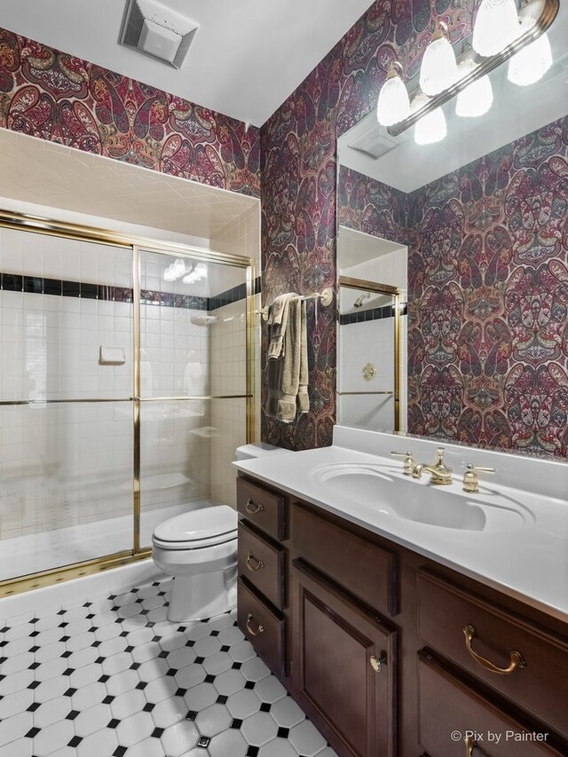 bathroom with an enclosed shower, vanity, and toilet