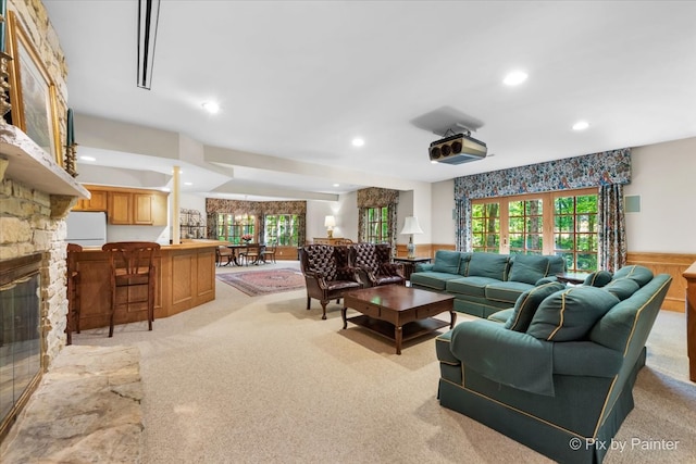 living room featuring a fireplace, light colored carpet, and a healthy amount of sunlight