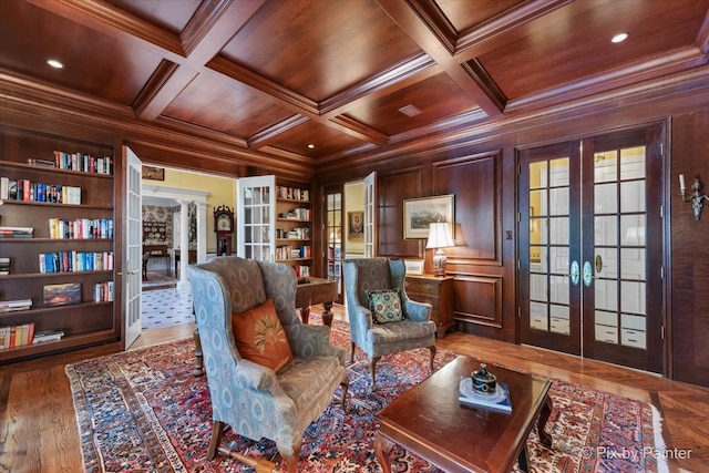 sitting room featuring crown molding, coffered ceiling, french doors, and wooden walls